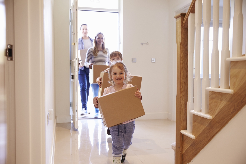 Family Carrying Boxes Into New Home On Moving Day